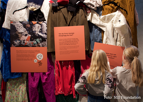 Students stand in front of a wall covered in clothes